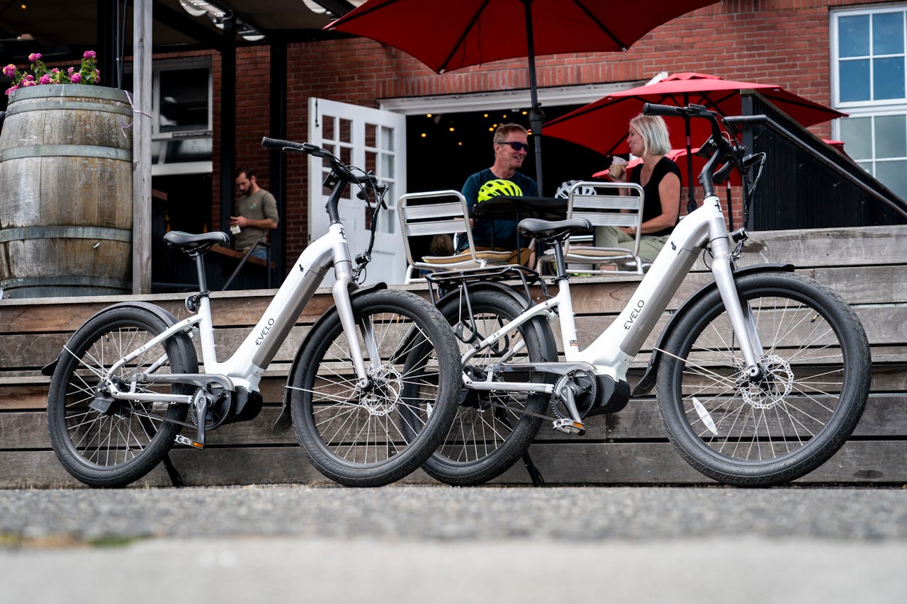 Two electric bikes parked outside a cafe in Seattle with people in the background.