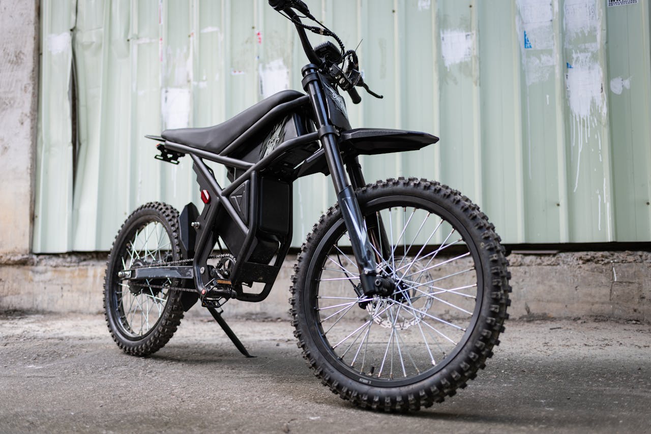 Sleek electric dirt bike parked outdoors, showcasing modern design and rugged tires.